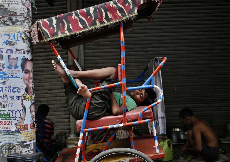 A man takes a nap on cycle rickshaw along roadside in Delhi