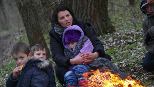 A Kosovar woman holds her child as they warm up around an open fire after they crossed illegally the Hungarian-Serbian border near the village of Asotthalom