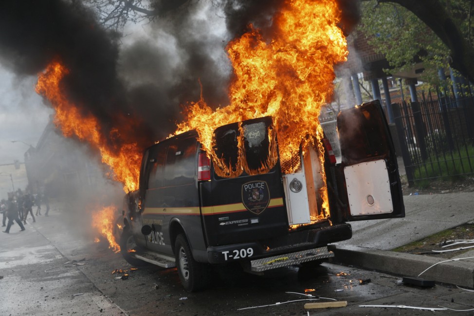 A Baltimore Metropolitan Police transport vehicle burns during clashes in Baltimore