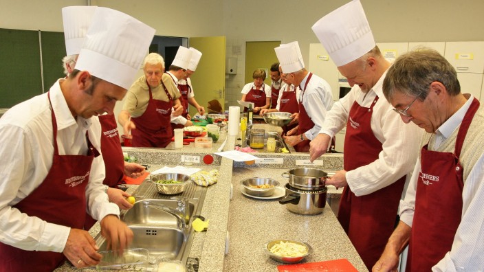 Kochkurse für Männer: Von den Kochschülern wird Erika Hinterberger (am Ende des Tisches) nur "Chefin" genannt, und selbst bezeichnen sie sich als "Hinterbergers Männer".
