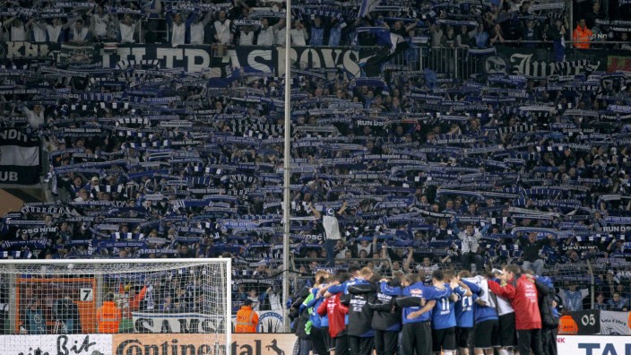 Arminia Bielefeld fans show their support as team gathers on the pitch after losing to VfL Wolfsburg in the German Cup in Bielefeld