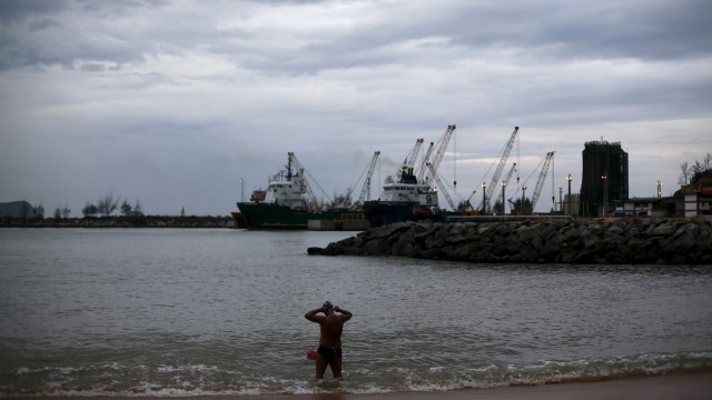 A man gets into the waters of a beach, next to a Petrobras offshore oil base in Macae