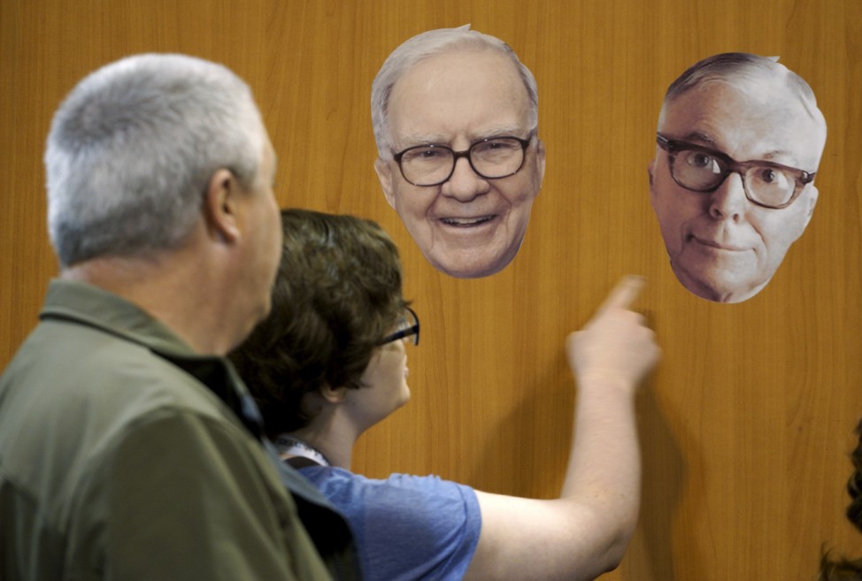 Berkshire Hathaway shareholders look at photos of Berkshire CEO Warren Buffett and vice-chairman Charlie Munger at the Berkshire-owned Fruit of the Loom booth at the shareholder's shopping day in Omaha