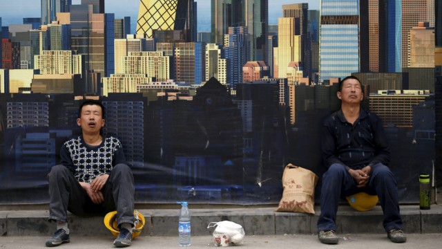 Construction workers take a nap in front of a wall of a construction site during their lunch break in Beijing