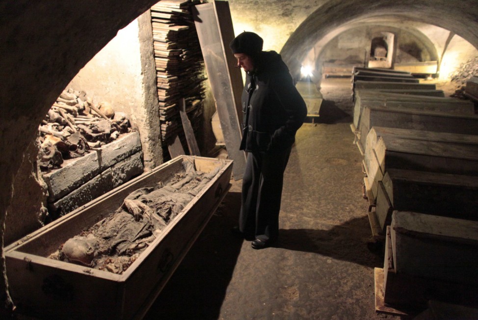 Visitor looks at a corpse in a coffin in the crypt under Mchaelerkirche in the centre of Vienna