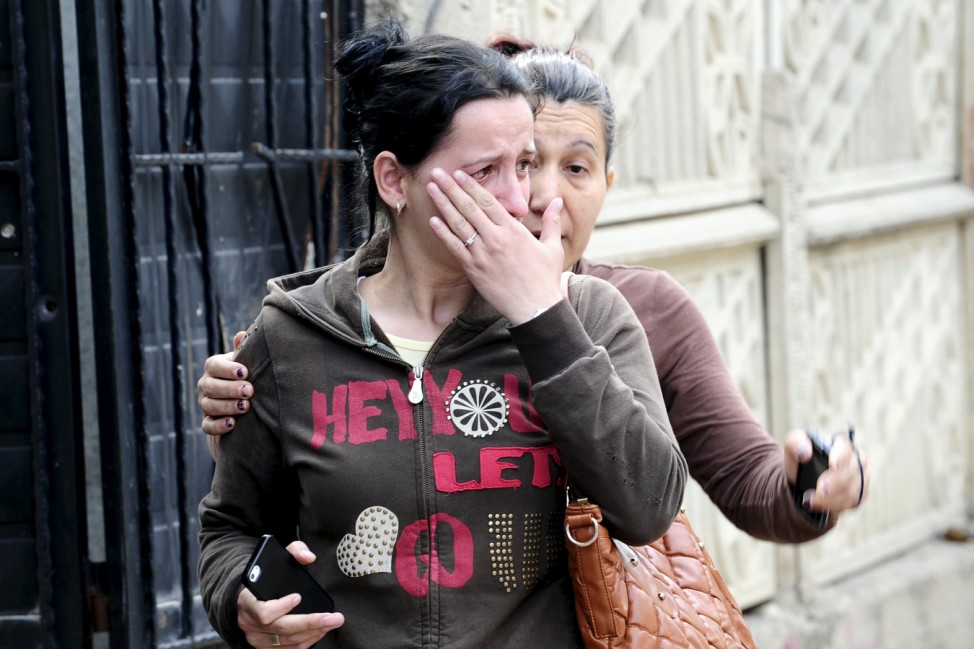A woman cries in front her house while her neighbour consoles her in Kumanovo