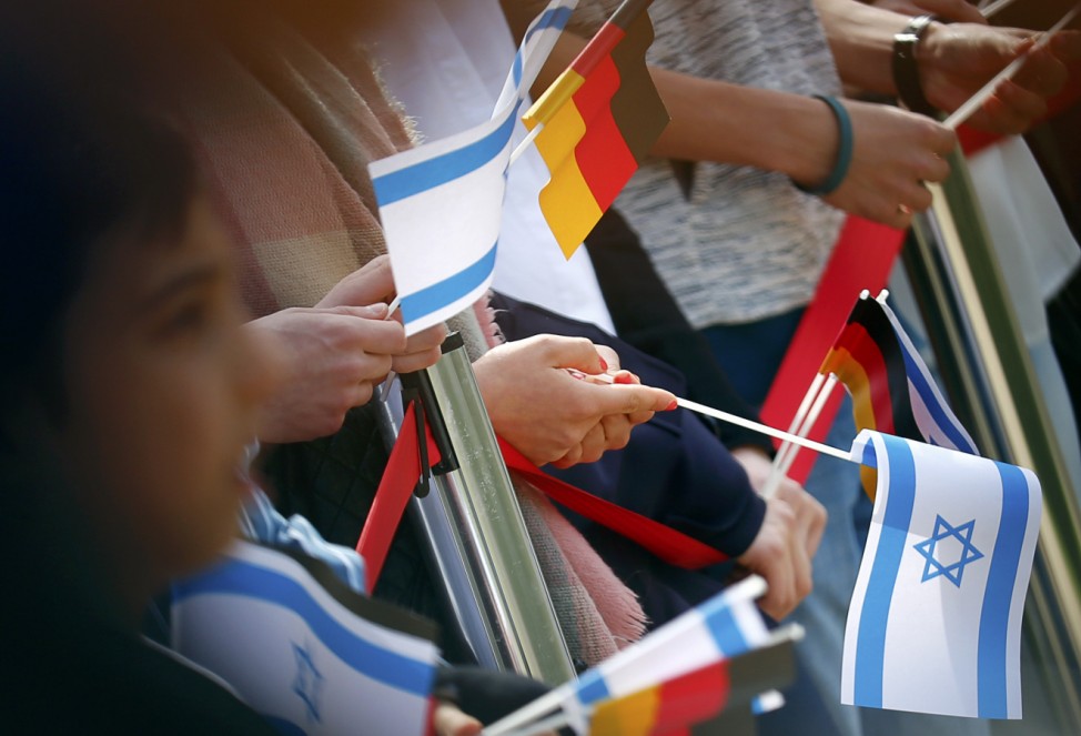 People hold German and Israeli flags as German President Gauck and Israeli President Rivlin attend a welcome ceremony at Bellevue presidential palace in Berlin