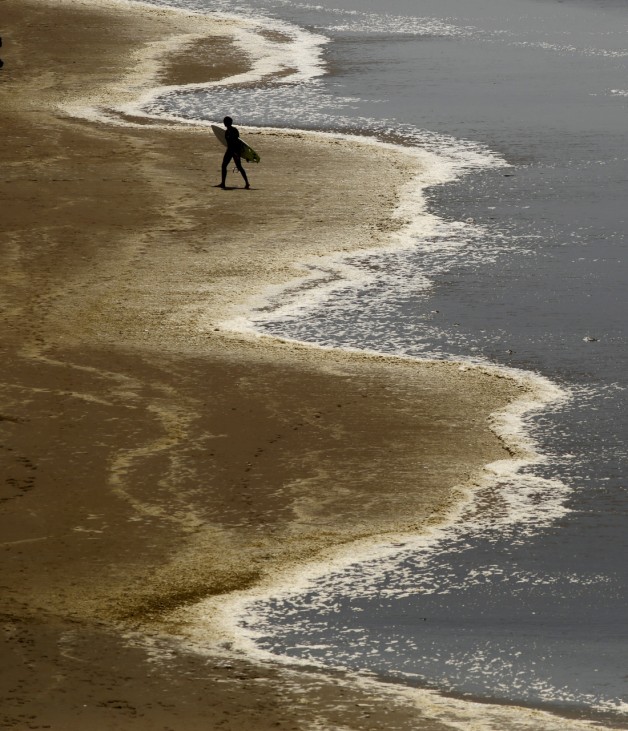 A surfer leaves the Pacific Ocean on Ocean Beach in San Francisco
