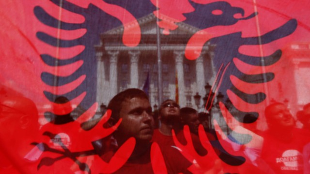 Anti-government protesters are seen through an Albanian flag as they demonstrate in front of Prime Minister Nikola Gruevski's government office in Skopje