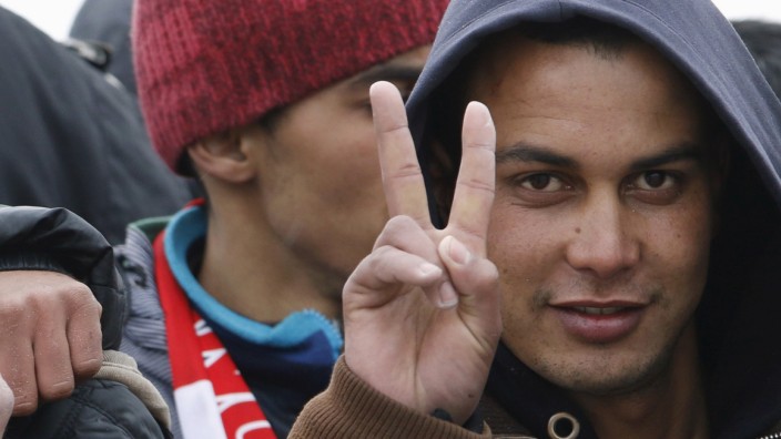 Moroccan citizen Touil Abdelmajid makes a victory sign as he arrives with migrants on the Italian navy ship Orione at Porto Empedocle harbour in Sicily
