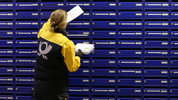 File photo of Deutsche Post postwoman dropping a letter into a mailbox