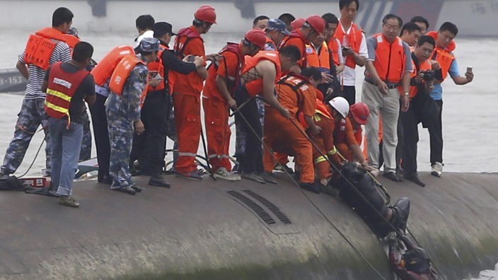 China: Rettungskräfte helfen einem Überlebenden, der aus dem Inneren des gekenterten Schiffs gerettet wurde.