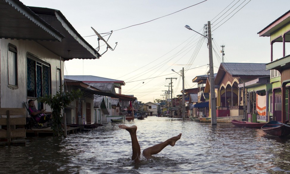 A child jokes in a street flooded by the rising Rio Solimoes, one of the two main branches of the Amazon River, in Anama