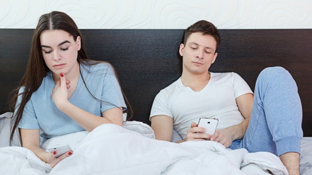 Young couple in their bed searching or browsing over internet