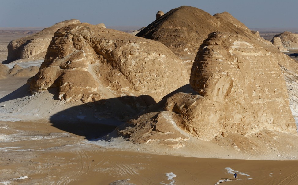 A man walks near rocks which are known as 'Ajabaat Rocks' in the White Desert near the Farafra Oasis southwest of Cairo