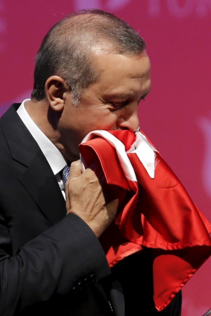 Turkey's President Erdogan kisses a handmade Turkish flag, given him as a gift from Ugandan university student Cemil, during a graduation ceremony in Ankara, Turkey