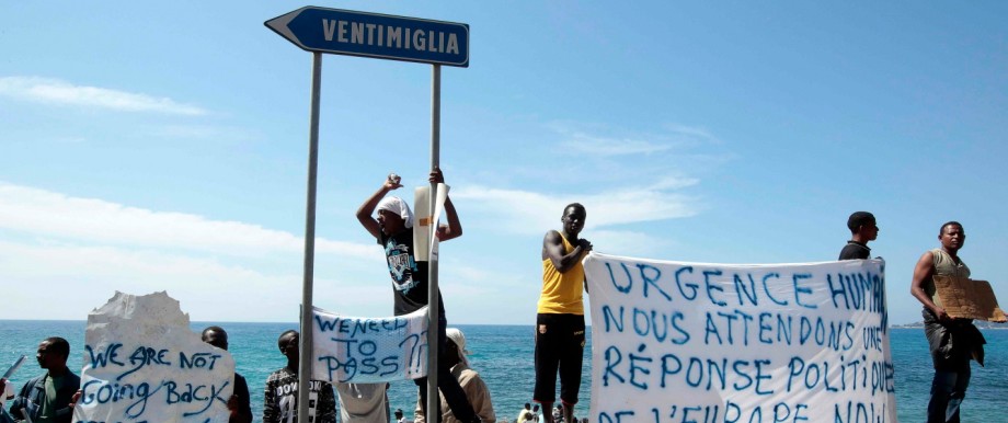 A group of migrants shout slogans and display a banner at the Saint Ludovic border crossing on the Mediterranean Sea between Vintimille, Italy and Menton