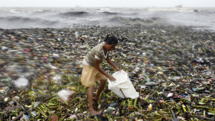 A woman balances on top of garbage at the height of Typhoon Nanmadol she collects recyclable materials along Manila Bay in Manila