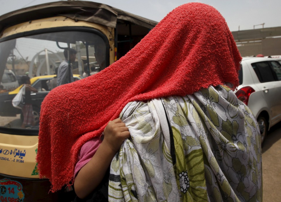 A child grabs her mother's scarf as they are both covered with a water-soaked towel, to beat the heat, in Karachi