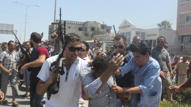 Police officers control the crowd while surrounding a man suspected to be involved in opening fire on a beachside hotel in Sousse