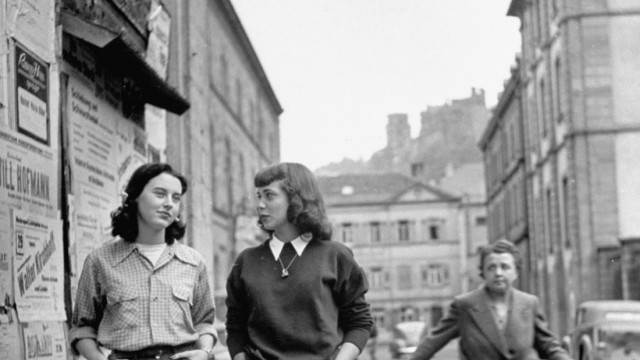 Two American students sauntering along a Heidelberg street, cause staid German women to look at them in wonderment.