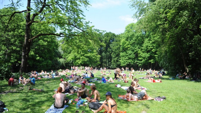 Sommer in München: Einen Platz an der Sonne suchen viele im Englischen Garten auf den Wiesen am Eisbach, bei Bedarf spenden die Bäume dort auch Schatten.