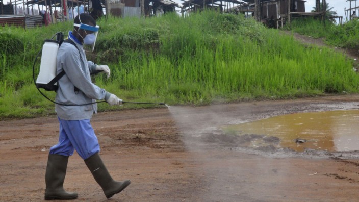 Ebola-Bilanz: In den Außenbezirken von Liberias Hauptstadt Monrovia versprüht ein Helfer ein Desinfektionsmittel, um weitere Ebola-Ansteckungen zu vermeiden.