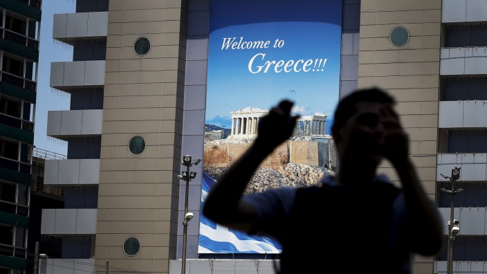 A man walks past a tourism poster in Athens, Greece