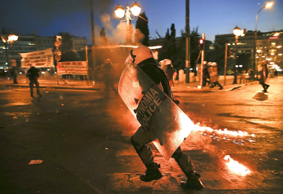 Riot police run as they disperse protesters during clashes in Athens