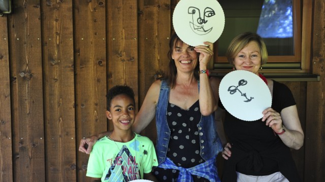 Gräfelfing: Die Ergebnisse des Bastelns von Masken präsentieren die Leiterinnen der Schule der Phantasie, Ulli Görg (Mitte) und Lilli Plodeck, mit einem kleinen Künstler.