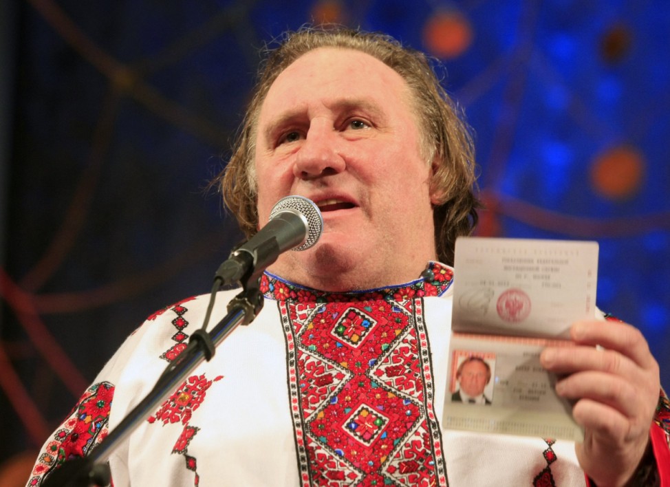French film star Gerard Depardieu, wearing a local costume, shows his passport during a ceremony in the town of Saransk