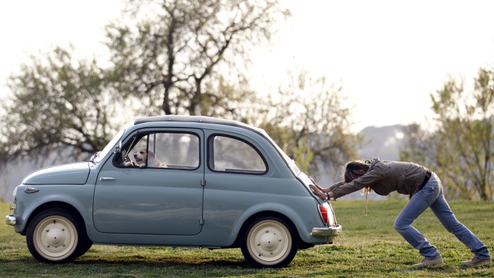 File photo of woman pushing her Fiat 500 car as her dog sits inside, in neighbourhood of Rome