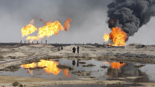 Excess gas is burned off near workers at the Rumala oil field