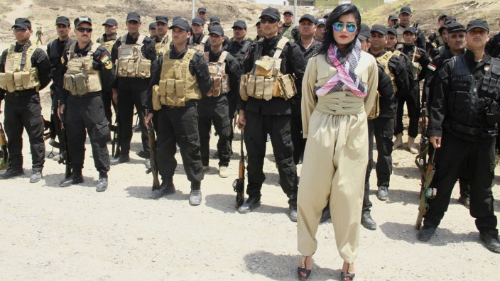 Kurdish pop star Helly Luv poses in front of Kurdish Peshmerga troops at a base in Dohuk