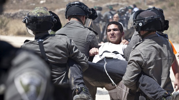 Israeli paramilitary police detain a Jewish settler protesting the demolition of two partially-built dwellings in the West Bank Jewish settlement of Beit El near Ramallah