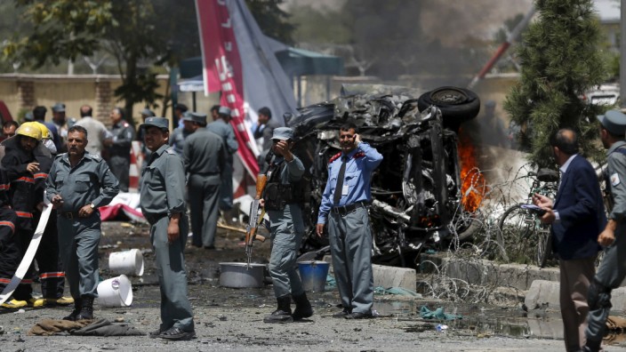 Policemen stand at the site of a car bomb blast at the entrance gate to the Kabul airport