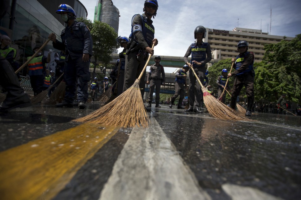 Police officers clean a street near the site of a deadly blast in central Bangkok
