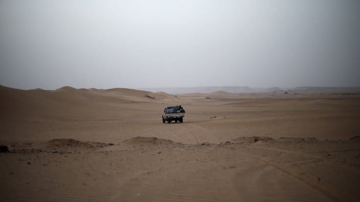 A vehicle transporting a group of African migrants drives through the desert on their journey from Ghat in southwest Libya