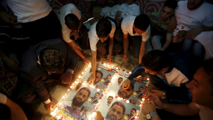 Palestinians light candles on posters depicting Palestinian detainee Mohammed Allan during a protest in support of Allan in the West Bank city of Hebron
