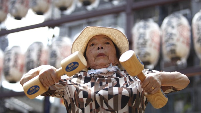 Woman exercises with wooden dumbbells during a health promotion event to mark Japan's 'Respect for the Aged Day' at a temple in Tokyo