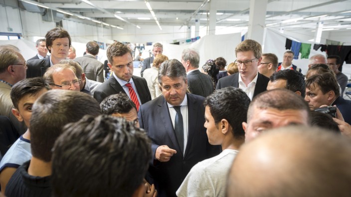 Germany's Vice Chancellor and SPD leader Sigmar Gabriel speaks with migrants from Syria and Afghanistan as he visits an asylum seekers accommodation facility in the eastern German town of Heidenau