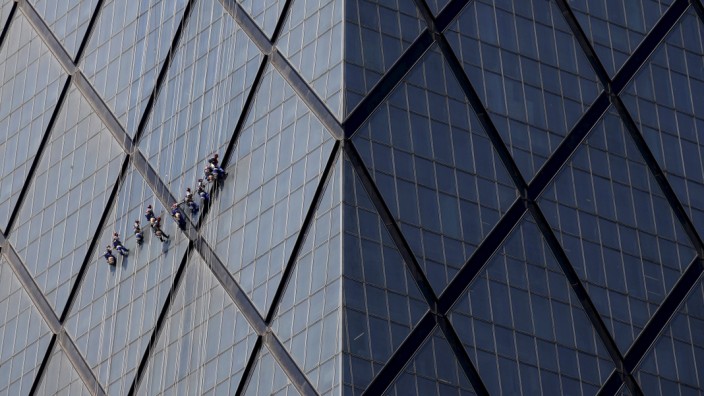 Workers clean windows of a building at a commercial district in Beijing