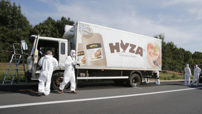 Forensic police officers inspect a parked truck in which up to 50 migrants were found dead on a motorway near Parndorf