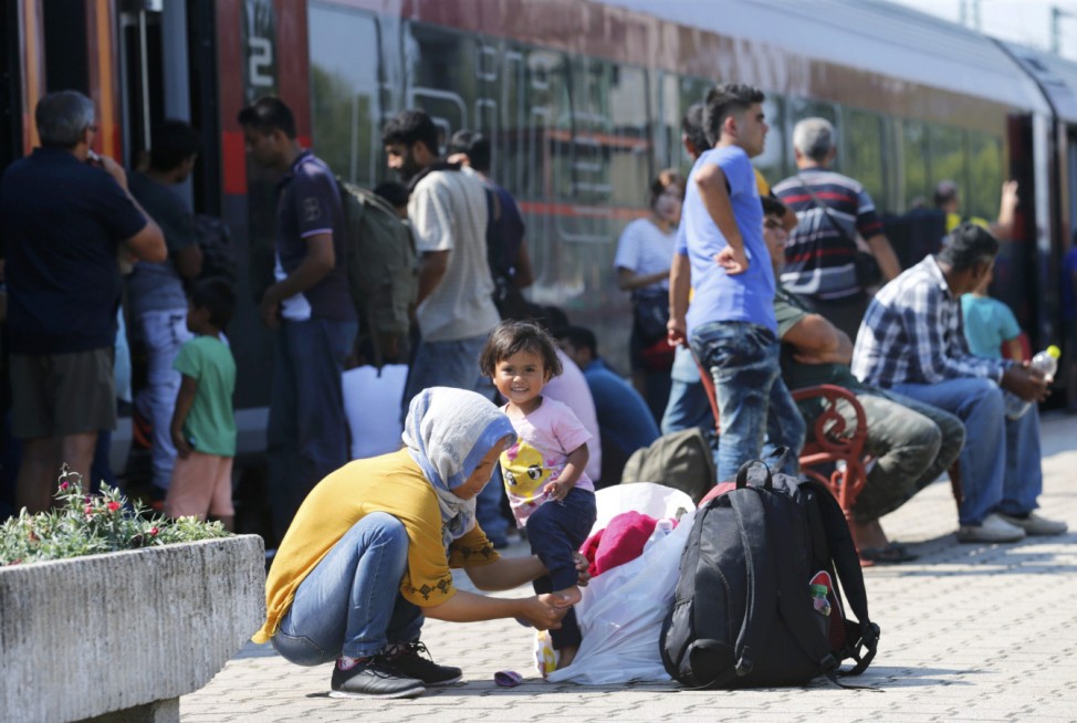 Travellers wait on a platform as a train heading for Austria, with migrants on board, is stopped for checks at a border station in Hegyeshalom