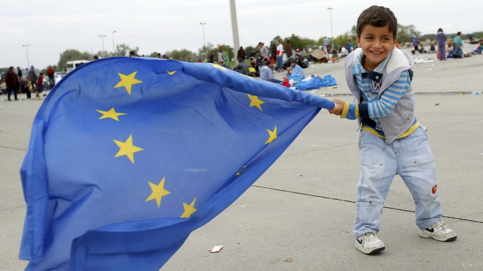 A young migrant child plays with a European Union flag after crossing the Austrian border in Nickelsdorf