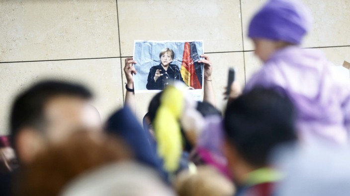 A migrant holds up a portrait of German Chancellor Merkel at a railway station in Vienna