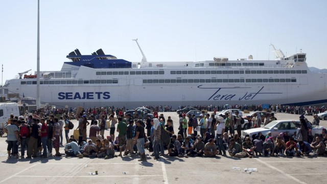 Refugees and migrants wait for a registration procedure to begin at the port of Mytilene on the Greek island of Lesbos