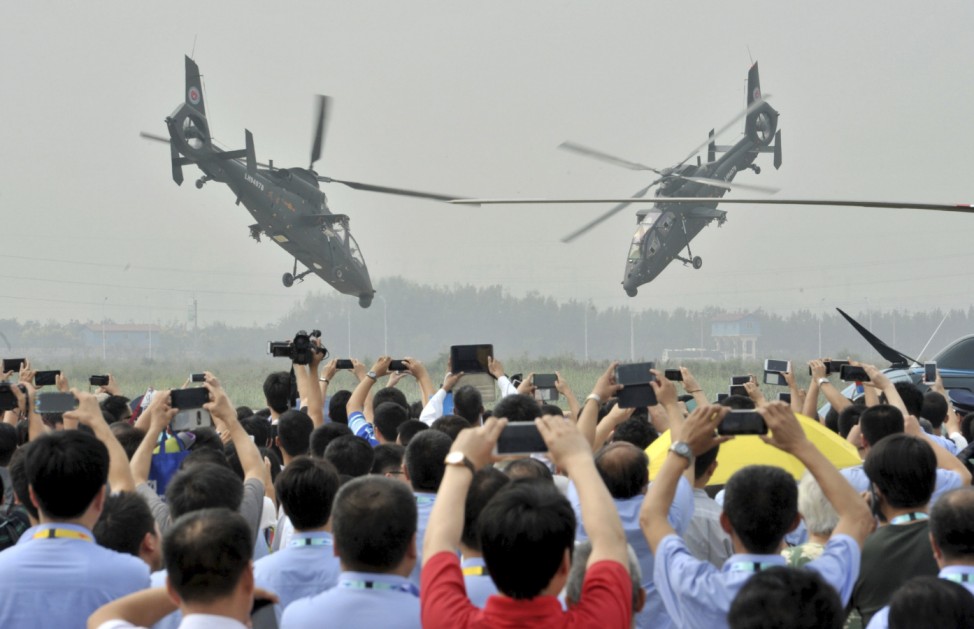 Spectators use their mobile phones to take pictures and videos as Z-19 helicopters of the People's Liberation Army (PLA) perform during an aerobatic display at the China Helicopter Exposition in Tianjin