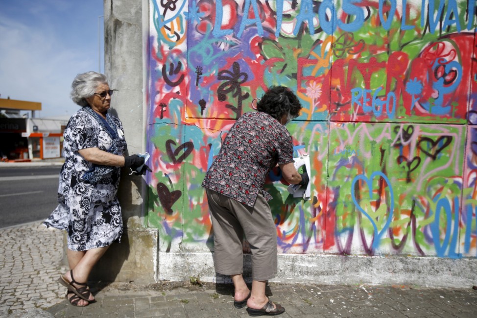 Women spray their designs on a wall during a graffiti class offered by the LATA 65 organization in Lisbon