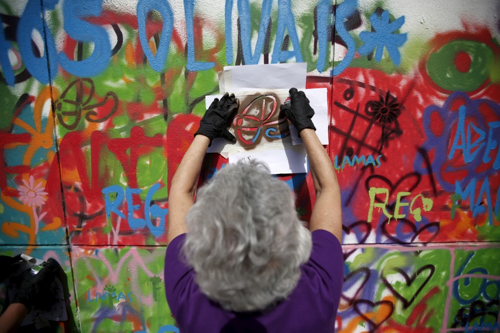 A woman sprays her design on a wall during a graffiti class offered by the LATA 65 organization in Lisbon